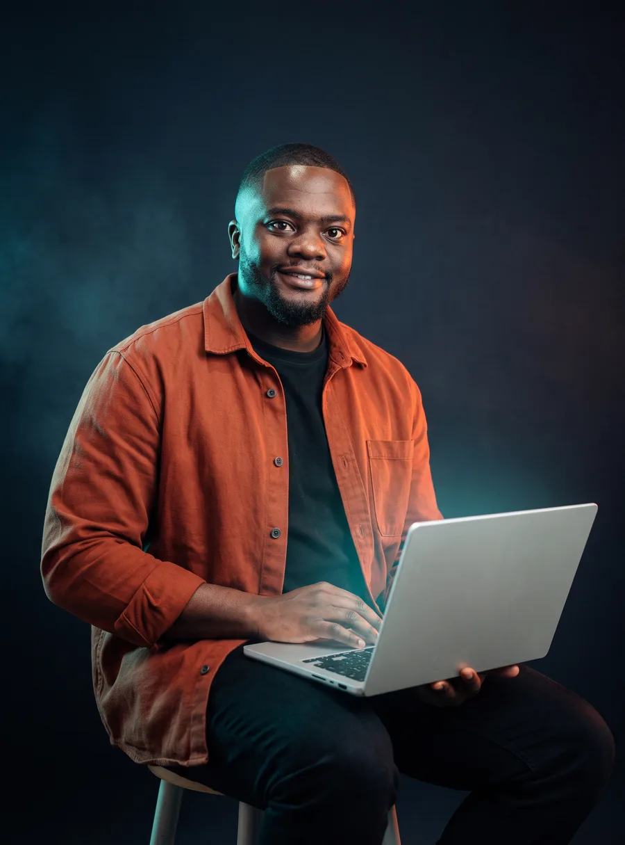 Darlington Chanakira, seated with a laptop on his knee, in a rust overshirt